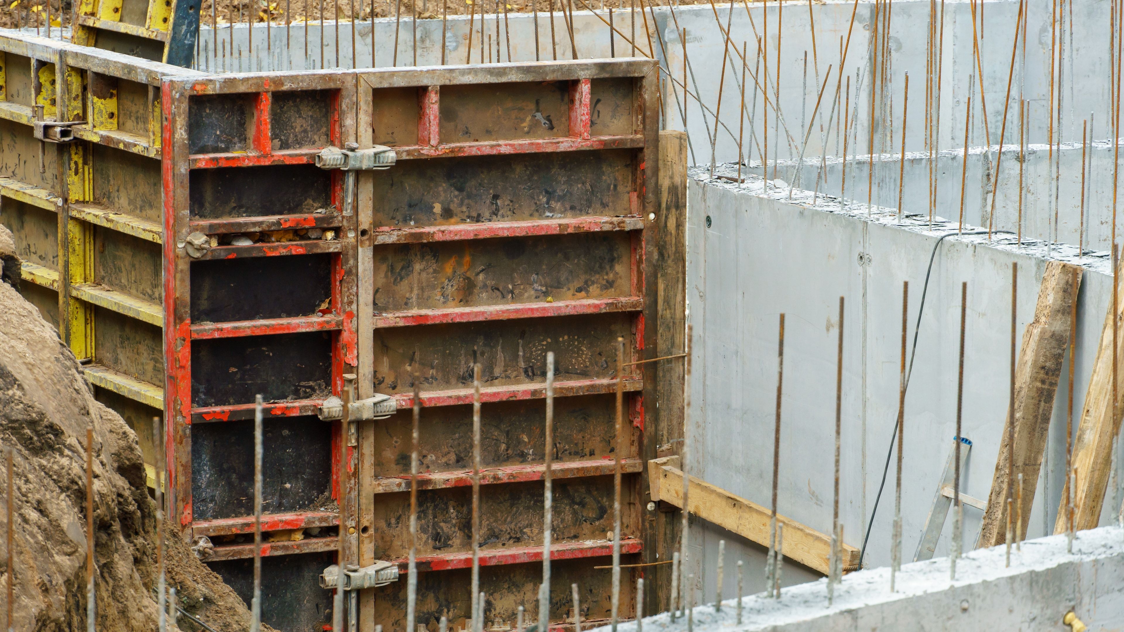 Panel de encofrado modular metálico de marco junto a un muro de hormigón en obra